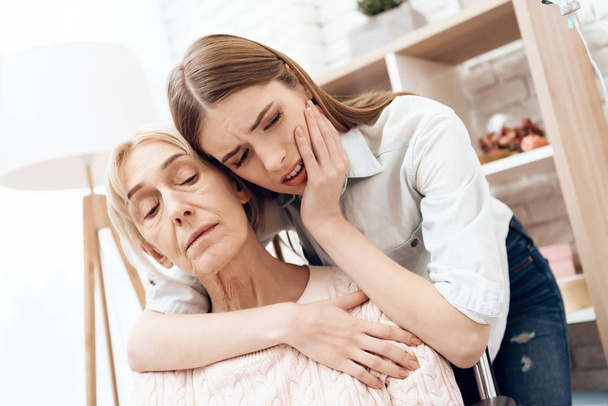 Girl worried and caring about elderly woman in wheelchair at home - Photo, image