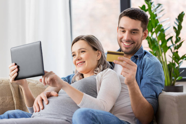 Mann und schwangere Frau kaufen zu Hause online ein - Foto, Bild