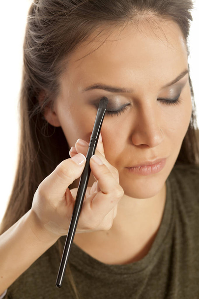 Visagist oogschaduw met een borstel toe te passen op een vrouw ooglid - Foto, afbeelding