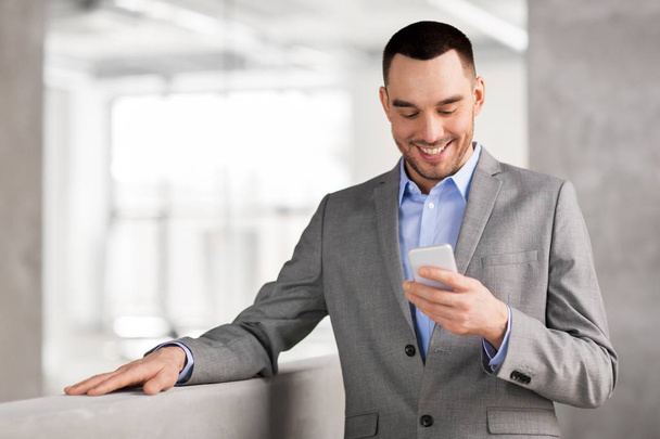 smiling businessman with smarphone at office - Foto, Imagen
