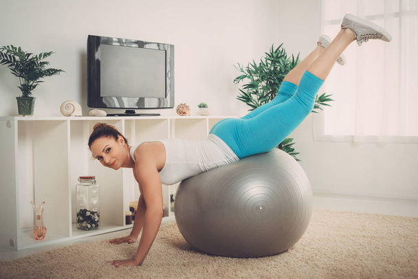 muscular smiling woman doing pilates exercise with online personal trainer on tv - Foto, Bild
