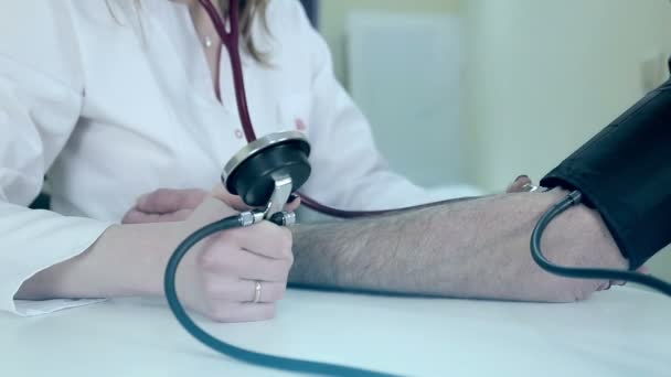 Doktor je žena, která měří tlak na pacientovi v lékařské místnosti - Záběry, video