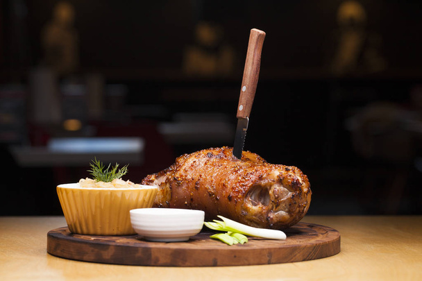 Restaurant dish - large baked pork knuckle on a wooden tray - Фото, зображення