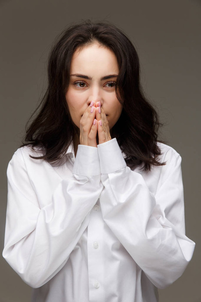 Beautiful girl in a white shirt shows emotions - hope. On a light background. - Foto, Imagem