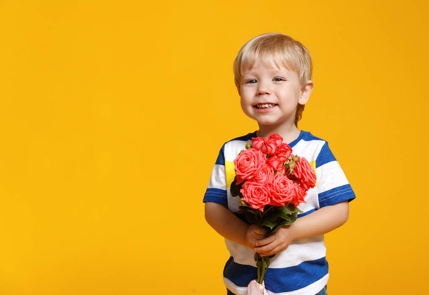 grappige babyjongen met boeket bloemen op gekleurde achtergrond - Foto, afbeelding