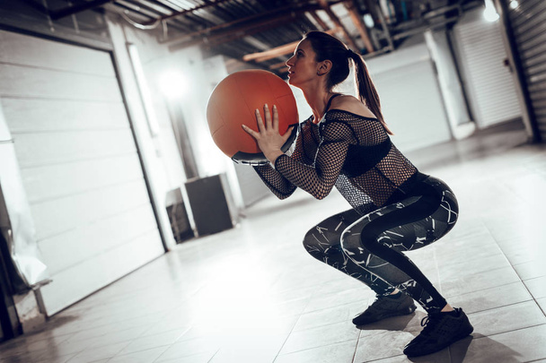 Jovem mulher muscular fazendo exercício com bola na garagem ginásio
 - Foto, Imagem