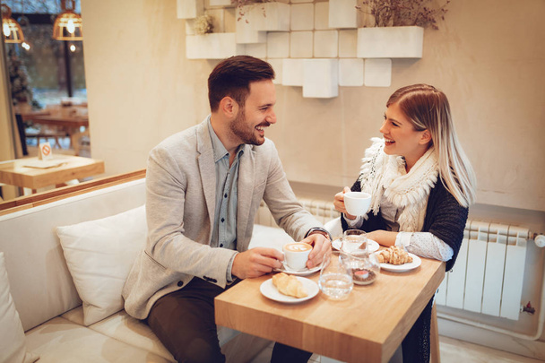 junges Paar trinkt Kaffee und isst Croissants im Café - Foto, Bild
