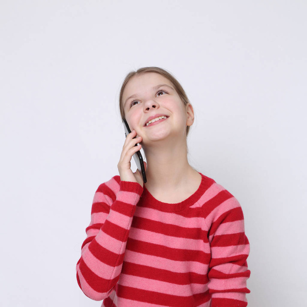 School teen girl holding mobile phone (smartphone) - Foto, afbeelding