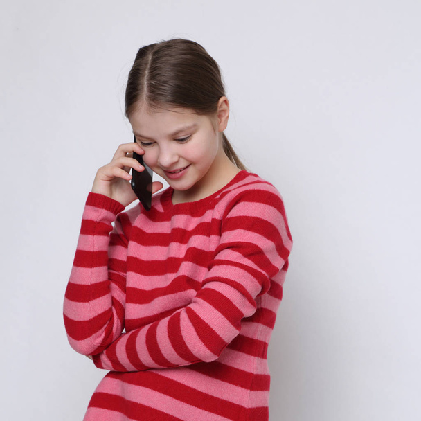 School teen girl holding mobile phone (smartphone) - Valokuva, kuva