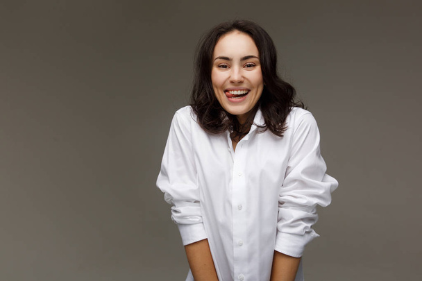 Beautiful girl in a white shirt shows emotions - smile, fun. - Fotó, kép