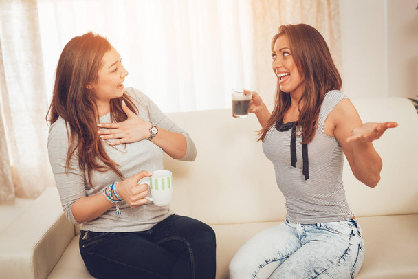 Dos jóvenes amigos alegres disfrutando del café y divirtiéndose en el apartamento
 - Foto, imagen