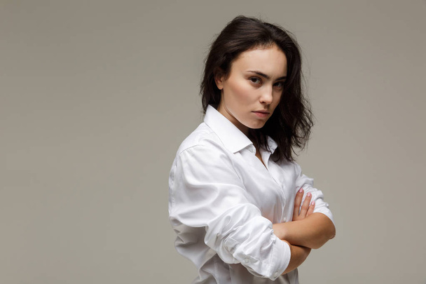 Beautiful girl in a white shirt shows emotions - disorder. On a light background. - Foto, Imagen