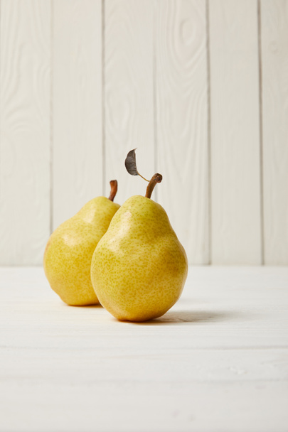 kaksi keltaista orgaanista päärynää puupohjalla
 - Valokuva, kuva