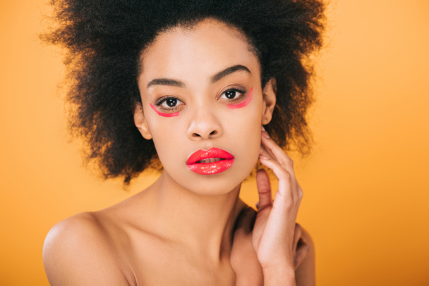 attractive young woman with creative red makeup and afro hairstyle isolated on yellow - 写真・画像