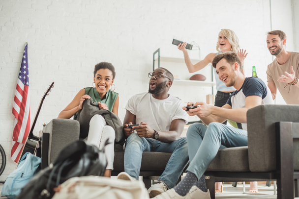 low angle view of happy multiethnic friends with joysticks playing video game - Foto, Bild