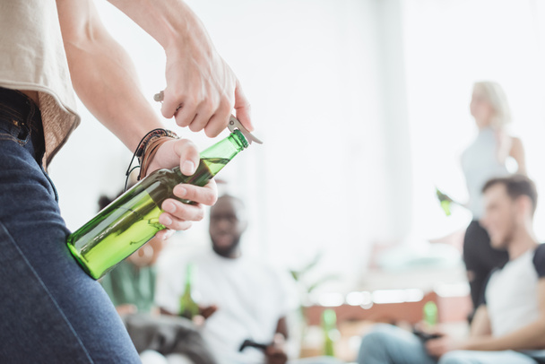 cropped image of man opening beer bottle by corkscrew  - Photo, Image