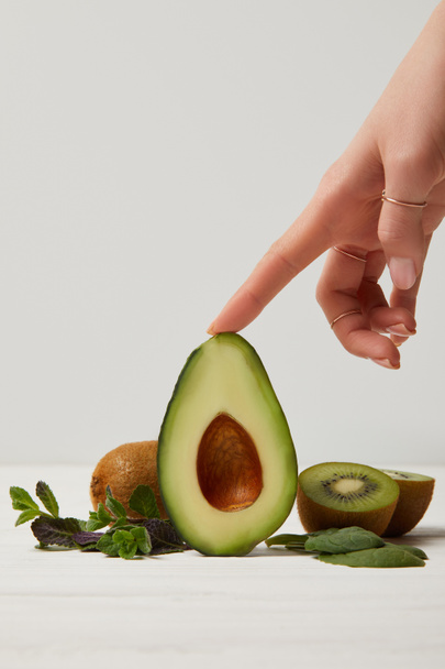 oříznutý pohled ženské ruky s zelené avokádo, kiwi a mátou - Fotografie, Obrázek