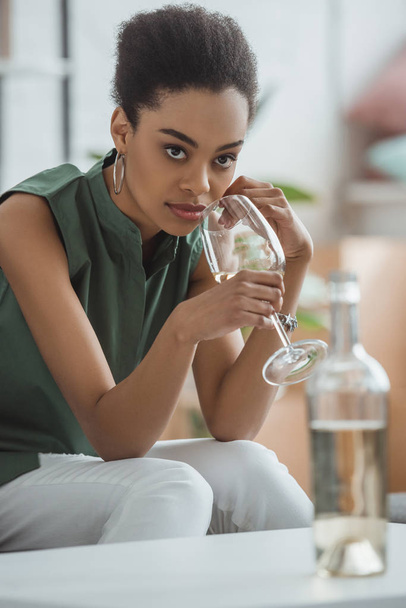 młody atrakcyjny african american kobieta picia białego wina ze szkła - Zdjęcie, obraz