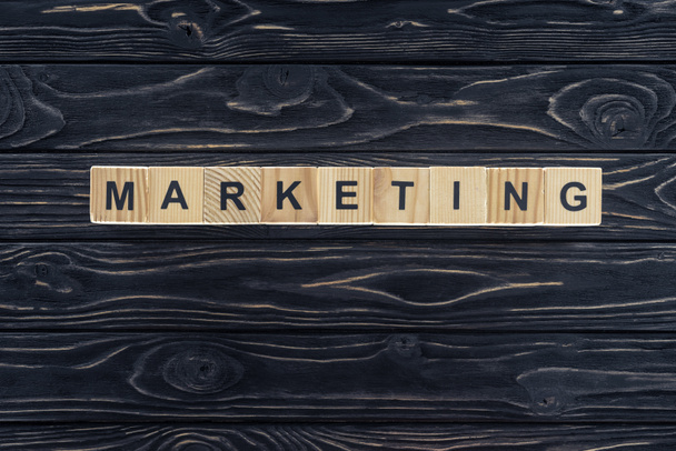 top view of word marketing made of wooden blocks on dark wooden tabletop - Foto, afbeelding