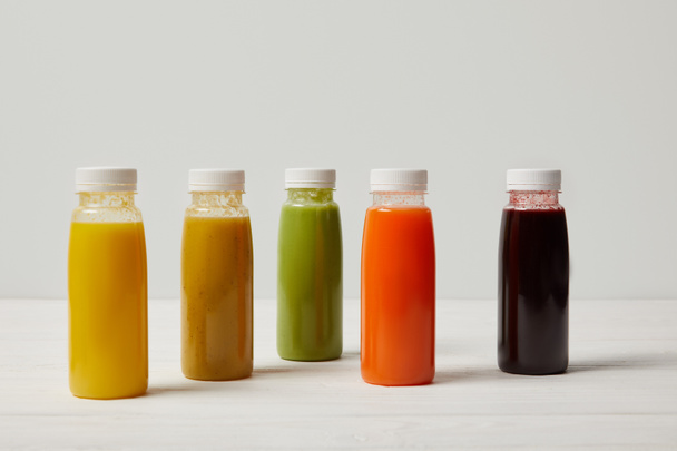 colorful detox smoothies in bottles on white wooden surface    - Photo, Image
