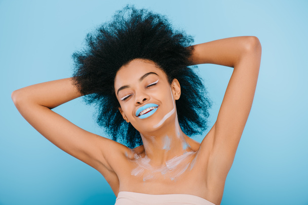 smiling young woman with creative makeup and blue lips isolated on blue - Foto, Imagem