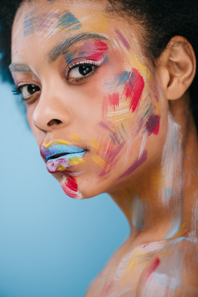 bella giovane donna con tratti di vernice sul viso isolato su blu
 - Foto, immagini