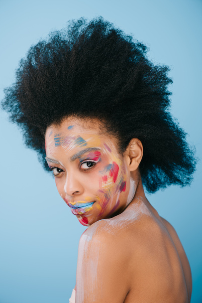 attractive young woman with paint strokes on face isolated on blue - Fotoğraf, Görsel