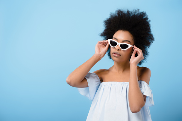 attractive young woman in stylish retro sunglasses isolated on blue - Fotoğraf, Görsel
