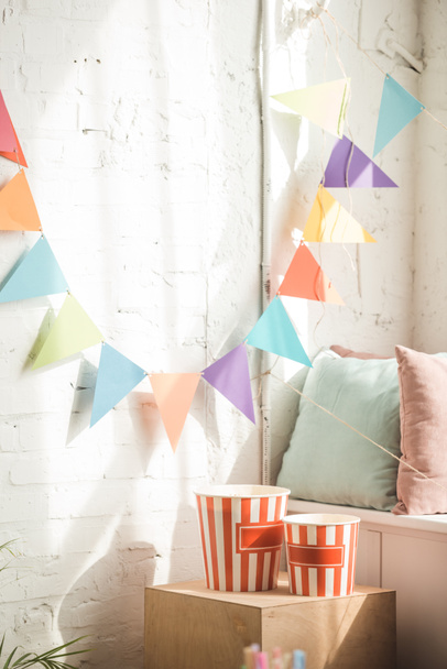 Party garland and popcorn buckets in light room - Photo, Image