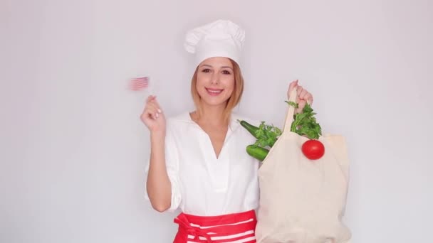 γυναίκα στο μάγειρα ομοιόμορφη εκμετάλλευση τσάντα με διαφορετικά λαχανικά και αμερικανική σημαία  - Πλάνα, βίντεο