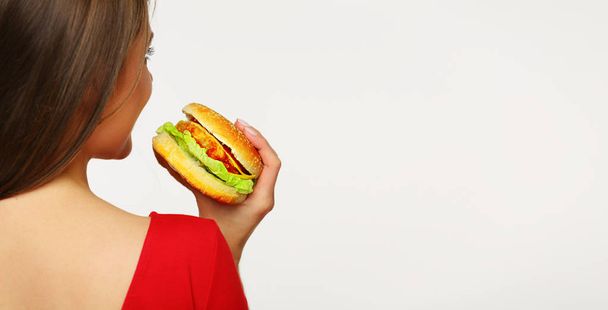 back view of beautiful woman in red dress holding burger isolated on white background  - Photo, Image