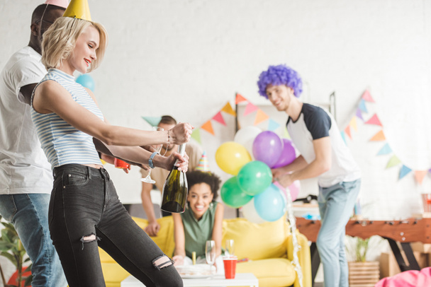 Kobieta blonde otwieranie szampana przed zabawa znajomi - Zdjęcie, obraz
