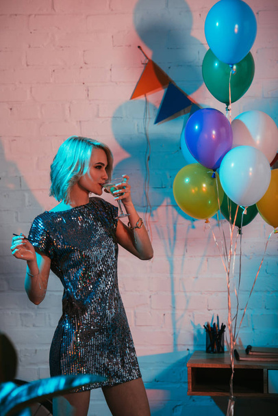 Blondine trinkt Cocktail auf Party mit bunten Luftballons - Foto, Bild