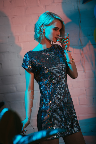 Attractive blonde girl drinking cocktail at party - 写真・画像
