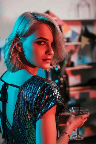 Attractive blonde girl holding glass with cocktail at party - 写真・画像