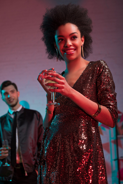 Mujer afroamericana sosteniendo vaso con cóctel de hombre en fiesta
 - Foto, imagen