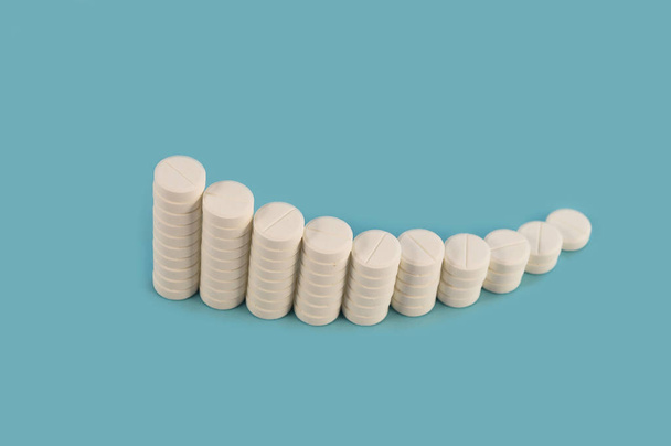 eine Reihe von Säulen mit weißen runden Tabletten, die sanft einen Bogen auf blauem Hintergrund biegen. - Foto, Bild