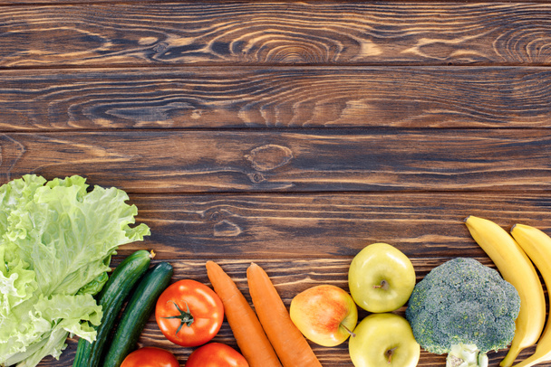 top view of fresh healthy fruits and vegetables on wooden table - Foto, afbeelding