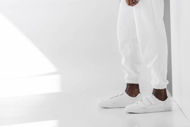 imagen recortada de hombre afroamericano con estilo en ropa blanca y zapatos de goma en blanco
 - Foto, Imagen