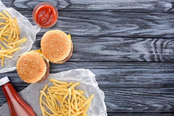 pohled shora na hamburgery s hranolky a kečupem na dřevěný stůl     - Fotografie, Obrázek