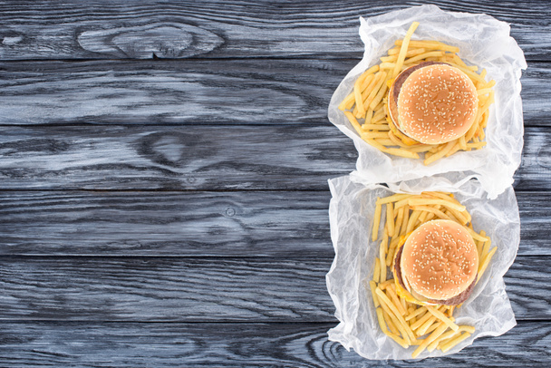 top view of two hamburgers with french fries on wooden table   - Photo, Image
