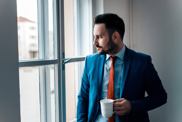 Businessman drinking a coffee and looking out of a window. - Foto, Imagen