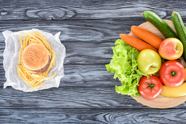 top view of hamburger with french fries and fresh fruits with vegetables on wooden table  - Photo, Image