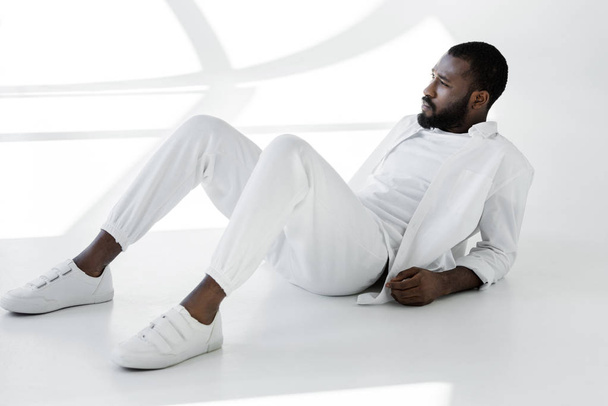 handsome stylish african american man in white clothes lying on white - Fotografie, Obrázek