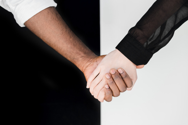körülvágott kép multikulturális pár kézen fogva, yin yang koncepció - Fotó, kép
