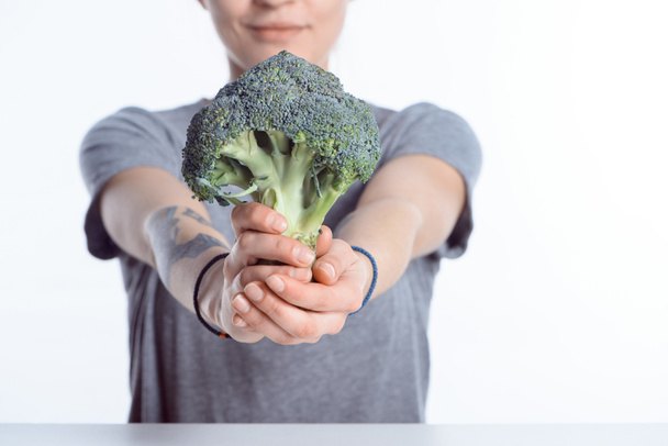 Nahaufnahme einer Frau, die frischen reifen Brokkoli in der Hand hält - Foto, Bild