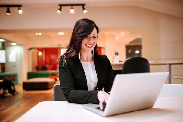 Sorridente giovane donna con auricolari godendo di chat online sul suo computer portatile
. - Foto, immagini