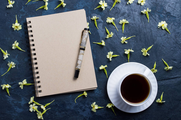 Tasse de café, carnet et fleurs sur fond bleu foncé. F
 - Photo, image