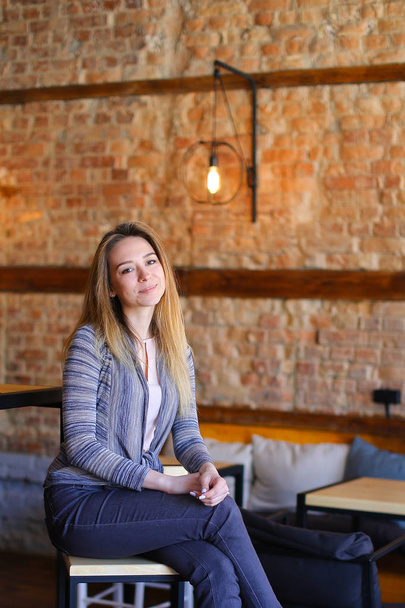 Satisfied girl sitting near table in cozy cafe with unusual interior. - Foto, afbeelding
