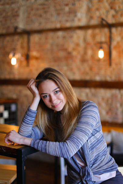 Satisfied girl sitting near table in cozy cafe with unusual interior. - Photo, Image